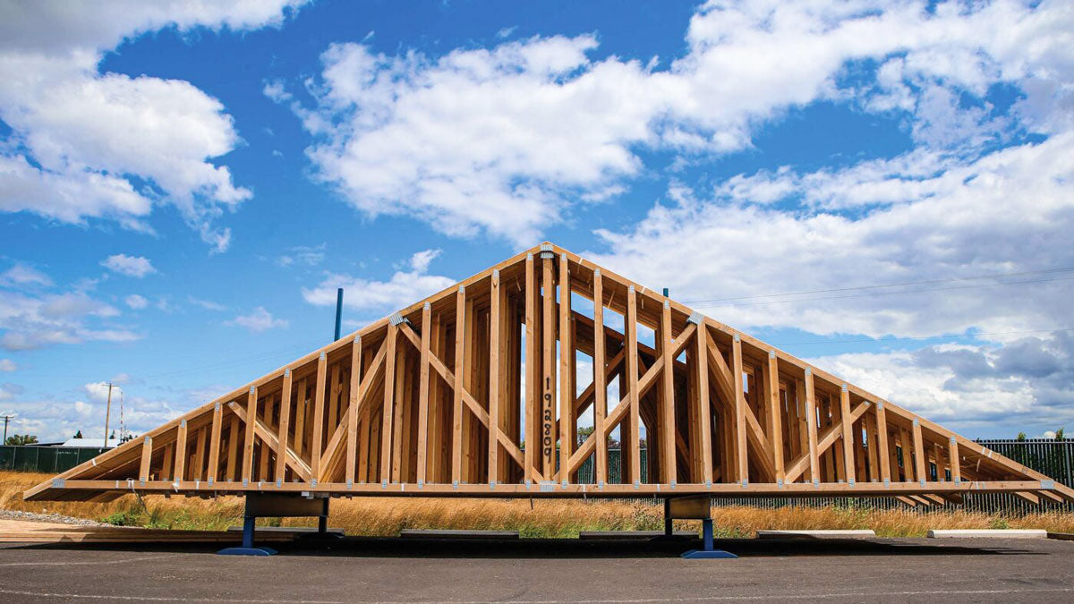 Engineered wood roof trusses with heavy galvanized connector plates bundled for Arkansas jobsite delivery.