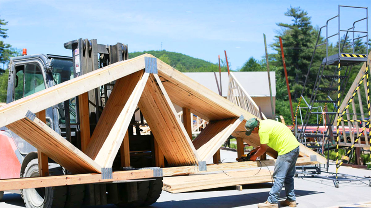 Engineered wood roof trusses with heavy galvanized connector plates bundled for Alabama jobsite delivery.