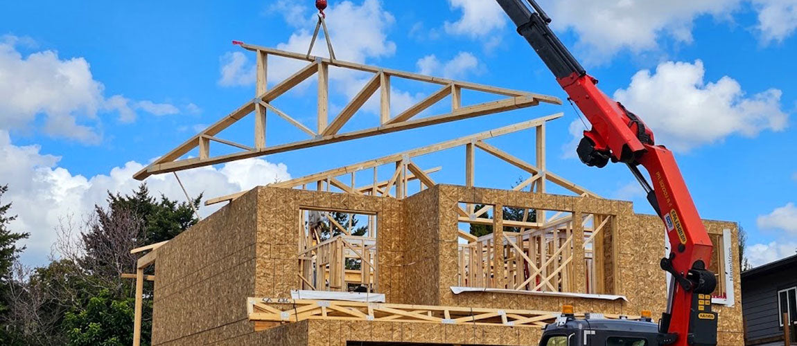 Mobile hydraulic crane hoisting clear-span wood roof trusses onto an active multi-family jobsite in Brazos County, Bryan, TX.