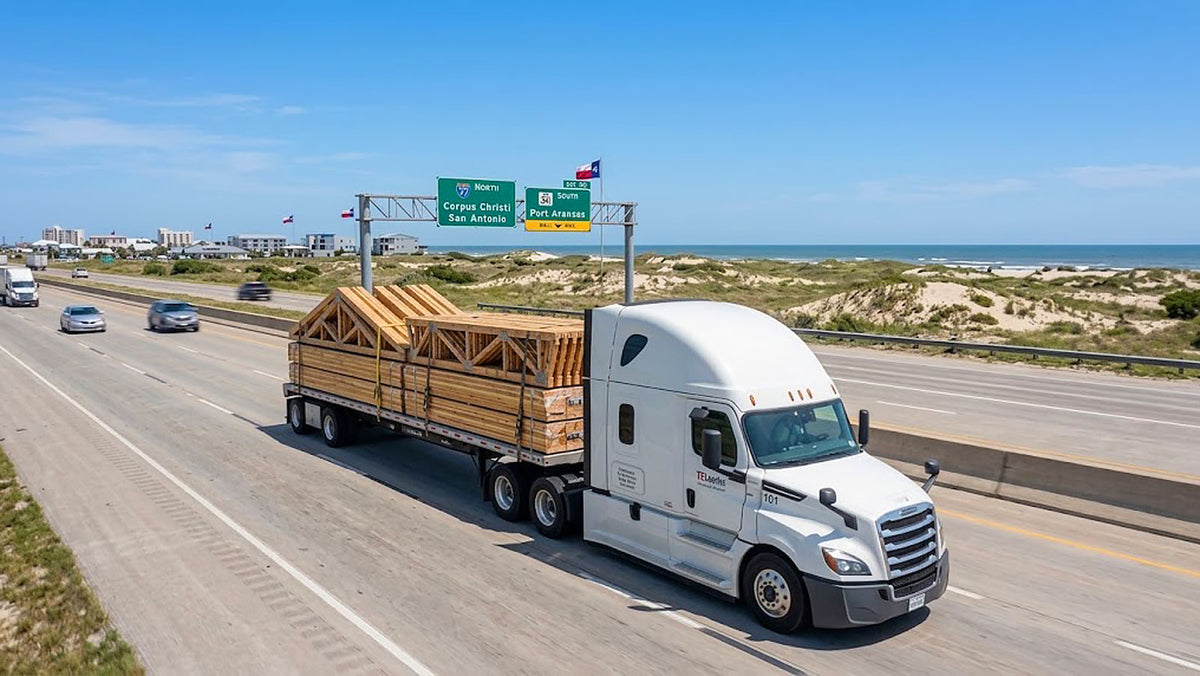 American Truss flatbed truck transporting banded timber roof trusses along TX-361 toward Port Aransas, Texas.